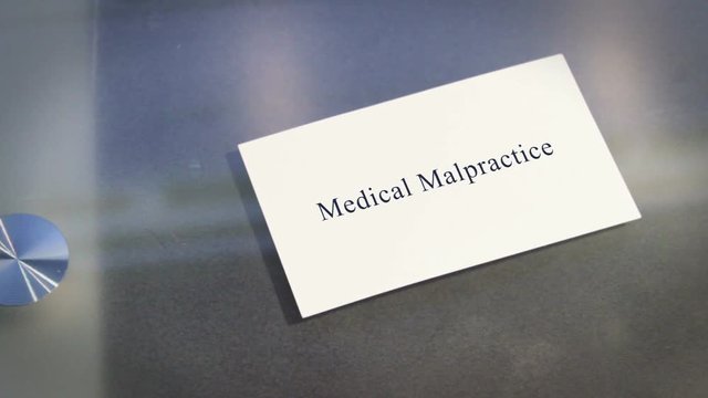 Hand puts business card on table with text medical malpractice