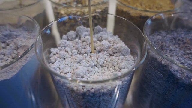Various types of polymer pellets and powders in plastic containers. Shot in motion