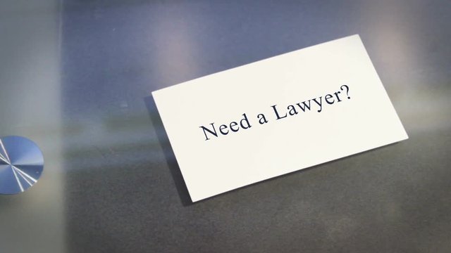 Hand puts business card on table with text Need a Lawyer