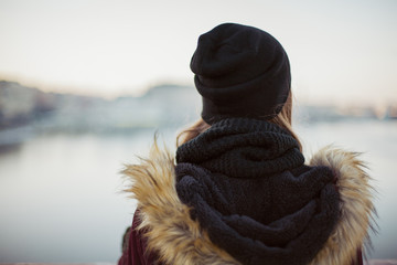 Back view of a sad hipster girl against blurred winter background