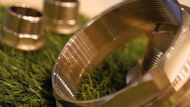 Brass and plastic plumbing parts on the surface of artificial grass. Shot in motion. Closeup. Dolly shot. Shallow depth of field. Rack focus