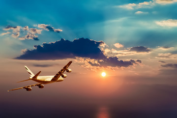 A plane flying towards a beautiful sunset