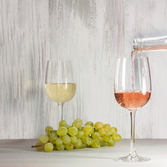 Rose wine poured into glass, with grapes in background