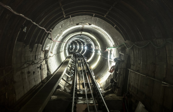 Underground mine pit tunnel gallery with working rail tracks - Industrial concept with transport and connection under earth