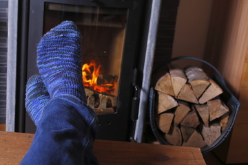 &uuml;bereinandergeschlagene F&uuml;&szlig;e vor Kamin, gem&uuml;tlich