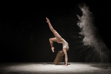 Graceful blonde dancing in white dust studio shot