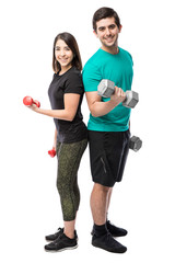 Happy couple lifting weights in a studio