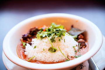 piece of beef in red curry sauce with vegetables and rice