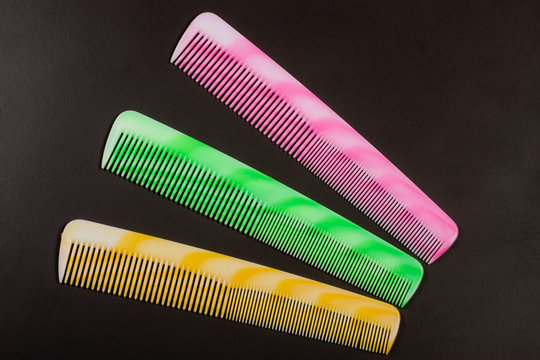 Three different colored hairbrushes on a dark background