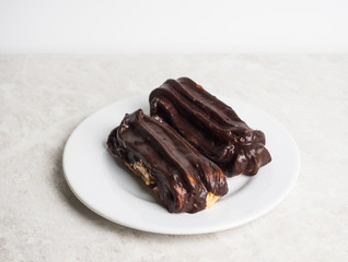 Chocolate eclair on the white table. Shallow depth of field.