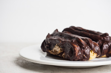 Chocolate eclair on the white table. Shallow depth of field.