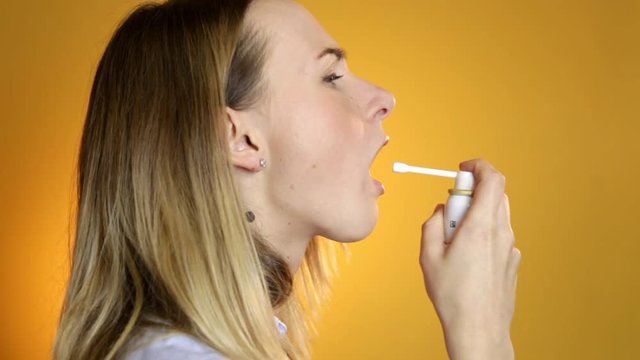 Girl with quinsy taking medicine on yellow background