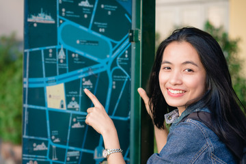 girl on street in Bangkok point to map