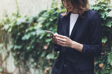 Portrait young businesswomen in black suit using smartphone isolated on background green nature wall mockup, pretty hipster manager holding mobile gadget, girl smile and texting message, connect