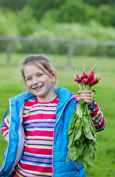 happy little girl holding a bunch of radishes