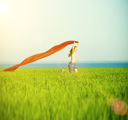 Young lady runing with tissue in green field. Beautiful happy woman walking in the summer rural meadow. Beautiful fit tan girl. Sexy slim model caucasian ethnicity outdoors.