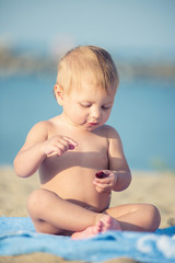 Baby playing with toys on the sandy beach near the sea. Cute little kid in  sand on tropical beach. Ocean coast.