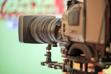 Fototapeta na wymiar The camera with a long lens. Recording TV program. On green background.