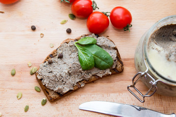 pate on the piece of bread with basil leaves and tomatoes