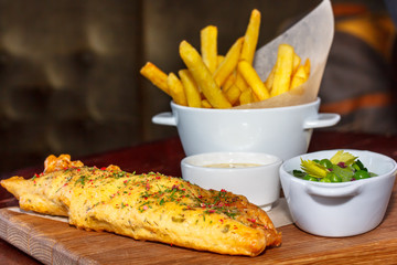 Fish and chips in the restaurant on a wooden Board.