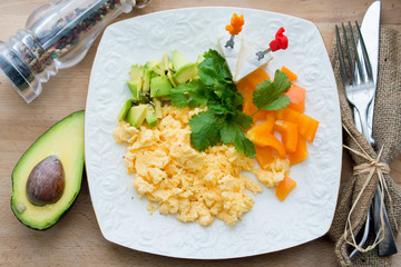 scrambled eggs with green and orange paprica avocado on the whit