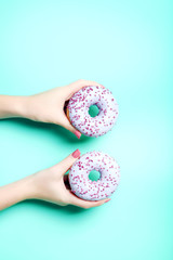 Female hands holding sweet donut on green background