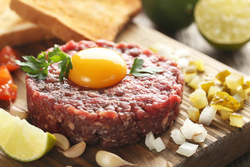 Beef tartare with egg yolk on a grey wooden table