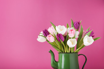 Bouquet of tulips in jug on pink background