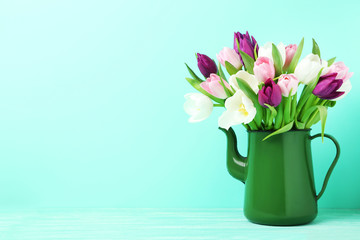 Bouquet of tulips in jug on green background
