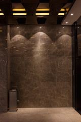 Abstract interior room with marble wall of brown color near the elevator with spot lights