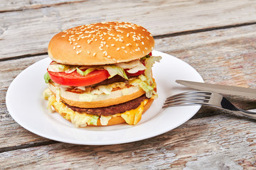 Hamburger on plate near cutlery.