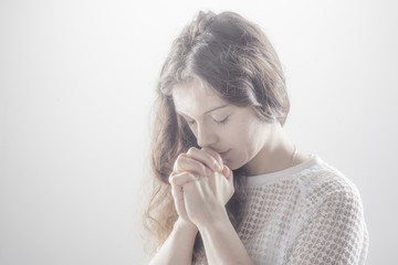 Praying woman on white background with shine. - obrazy, fototapety, plakaty
