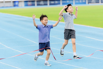 Fototapeta premium Young Asian boy running on blue track in the stadium