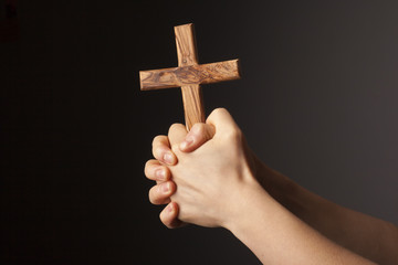Hands with cross on dark background