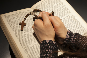 Hands of young woman with holy bible and rosary