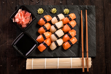 Various kinds of sushi served on a platter with soy sauce, wasabi and pickled ginger.