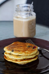 blueberry pancakes with maple syrup and a jug of coffee