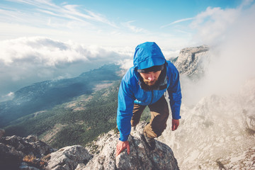 Man Traveler climbing on mountain summit over clouds Travel Lifestyle success concept adventure...
