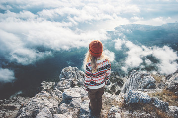 Woman traveler on mountain summit over clouds enjoying aerial view Travel Lifestyle success concept...