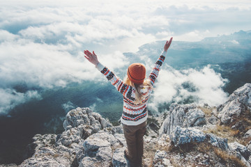 Happy woman traveler on mountain summit hands raised over clouds Travel Lifestyle success concept...