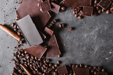 Coffee beans and dark chocolate. Chocolate bar . Background with chocolate. Coffee beans. Cinnamon sticks and star anise.  A large bar of chocolate on gray abstract background.