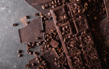 Chocolate, coffee beans. and cocoa powder. Chocolate bar pieces. dark chocolate background. A large bar of chocolate on gray abstract background. Background with chocolate. Slices of chocolate