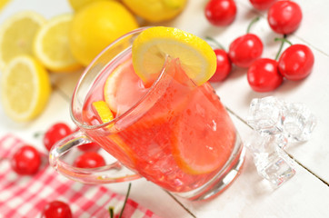 Fruit cherry ice tea with slice of lemon in mug and cherries