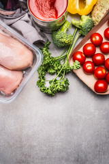Healthy food with raw chicken breast, fresh seasoning and vegetables on gray stone background