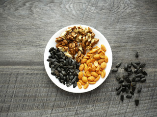 nuts ans sunflower seeds on a plate on wooden background
