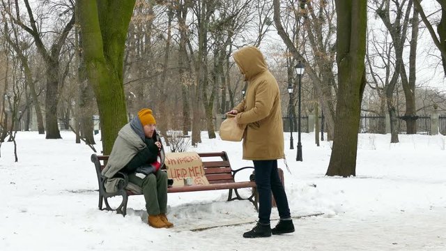 
4K. Some food  burger for Homeless  adult man in cold  winter city park  
