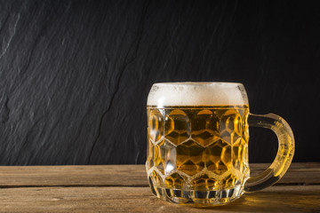 mug of beer on wooden table. front view
