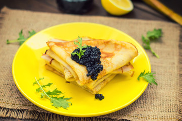 Black caviar on Russian pancakes - blini. Selective focus.