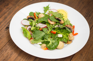 Fresh spring salad with radish, Mizuno, mushrooms grilled, Adygei cheese, spinach, bell pepper, lemon, corn. Wooden background