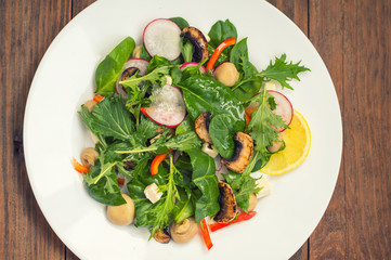 Fresh spring salad with radish, Mizuno, mushrooms grilled, Adygei cheese, spinach, bell pepper, lemon, corn. Wooden background